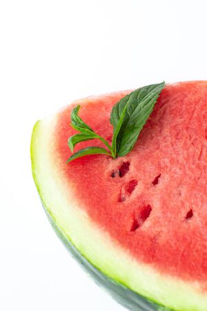 Sliced of fresh red ripe watermelon with green leaves of mint on white backgroundの写真素材