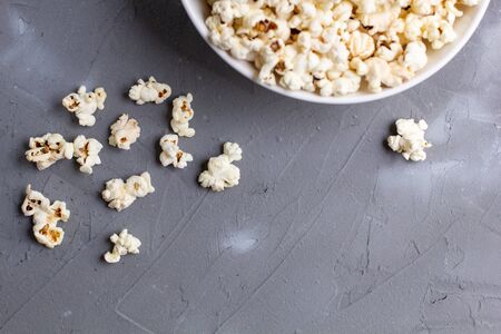 Popcorn in white bowl on grey table. Top view with copy space