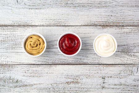 Set of three kinds of classic sauces on white wooden background. Mayonnaise ketchup mustard. top view with copy spaceの写真素材
