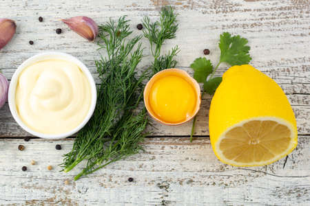 Border of ingredients of garlic sauce. Products for preparing mayonnaise on white wooden background. Top view with copy spaceの写真素材