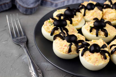 Deviled Eggs With A Spider For Halloween Party. Fun food for kids with napkin and forkの写真素材