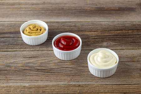 Set of three kinds of classic sauces on natural wooden background. Mayonnaise ketchup mustard. top...