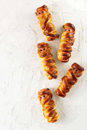 Scary sausage mummies in dough for kids party. Funny crazy Halloween food for children on white...