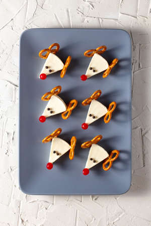 Funny christmas snack in a shapes of deer for kids party. Concept New year food from cheese and pretzels on white backgroundの写真素材
