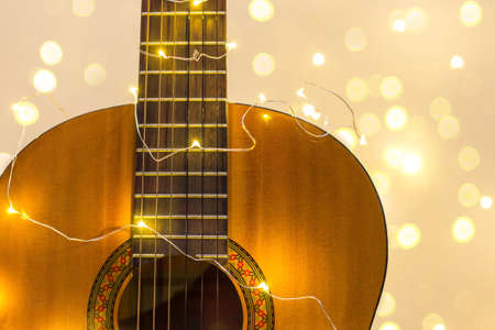acoustic guitar wrapped in a luminous garland with bokeh. Christmas gift with space for text