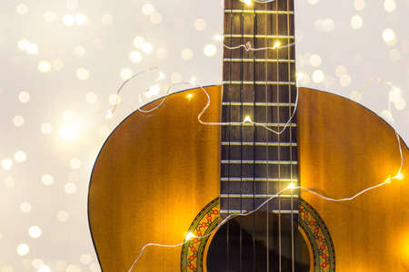 acoustic guitar wrapped in a luminous garland with bokeh. Christmas gift with space for text