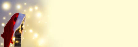 Banner of Acoustic Guitar with red Santa hat and light garland. Christmas music song concept with copyspace on white backgroundの写真素材