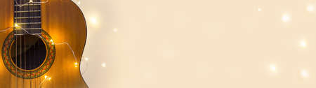Banner of acoustic guitar wrapped in a luminous garland. Christmas gift with space for text