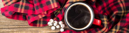 Banner of hot coffee in red cup and cozy plaid on natural wooden backgroundの写真素材