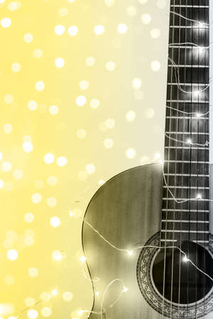 acoustic guitar wrapped in a luminous garland with bokeh. Christmas gift with space for text. Color...
