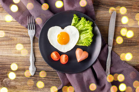 Valentines day breakfast with heart shaped fried eggs served on gray plate. flat lay, top view. with bokehの写真素材