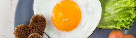 banner of Fried eggs in the shape of a heart with sausages, herbs and tomatoes. Breakfast for your...