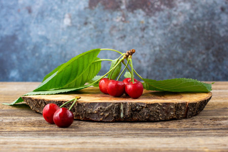 bunch of ripe sweet cherries with green leaves on wooden board