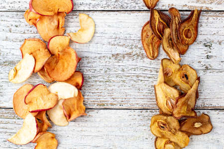 Border of a pile of dried pears and apples in slices on a white wooden background. Dried fruit chips. Healthy food. Top viewの写真素材