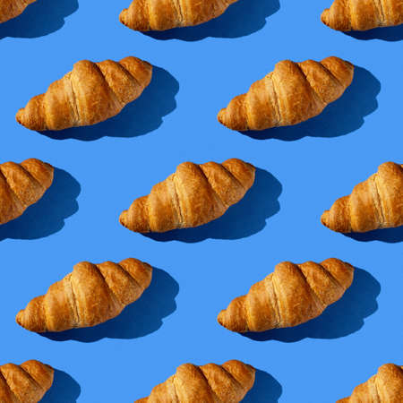 seamless pattern of tasty croissant on a blue background with hard lightの写真素材
