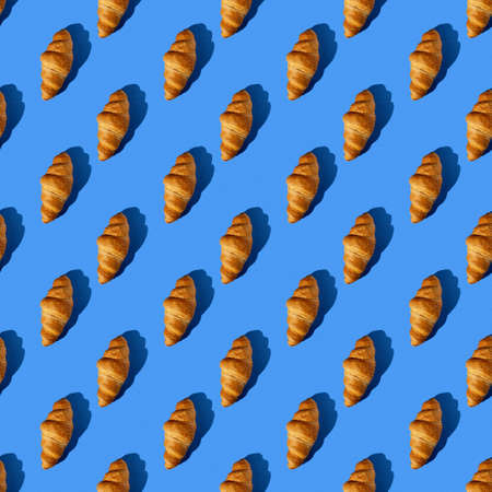 seamless pattern of tasty croissant on a blue background with hard lightの写真素材
