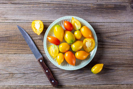 various colorful ripe tomato on wooden background. Cooking from yellow orange and red cherry tomatoes. Top view with copyspaceの写真素材