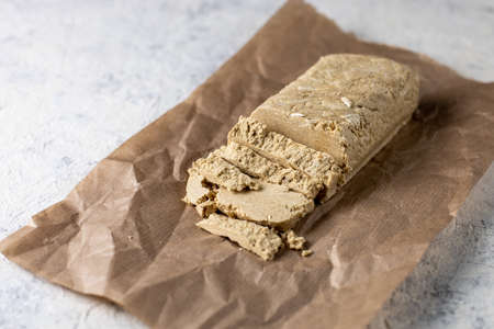 Cutted halva on craft paper. Sweet dessert with mint leaves on white background
