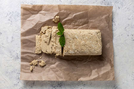 Cutted halva on craft paper. Sweet dessert with mint leaves on white backgroundの写真素材