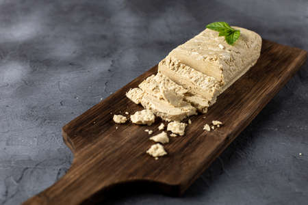 Slices of halva on cutting board. Sweet Turkish dessert with mint leaves on black backgroundの写真素材