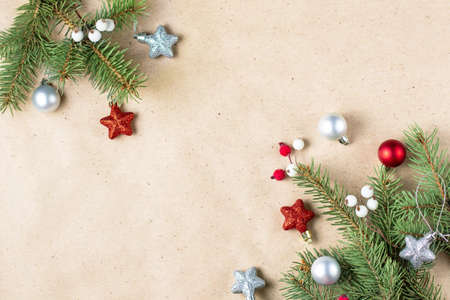 corner of fir tree branch with silver and red decoration on craft paper for christmas card with copy...
