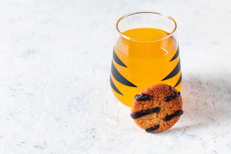 orange mandarin cocktail in glass with black stripes and cookies. Christmas holiday welcome drink. Concept for children new year with tree branchesの写真素材