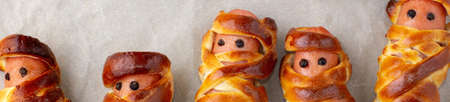 banner of Scary sausage mummies in dough for kids party. Funny crazy Halloween food for children on rustic backgroundの写真素材