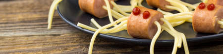 banner of spaghetti with sausages in the form of spiders. Happy kid food for Halloween party on wooden background. copyspaceの写真素材