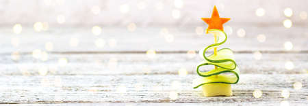 banner of Creative christmas tree of cucumber, cheese and star of carrot. Funny kids food for new year party on gray background with copy spaceの写真素材