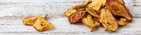 banner of A pile of dried pears in slices on a white wooden background. Dried fruit chips. Healthy foodの写真素材