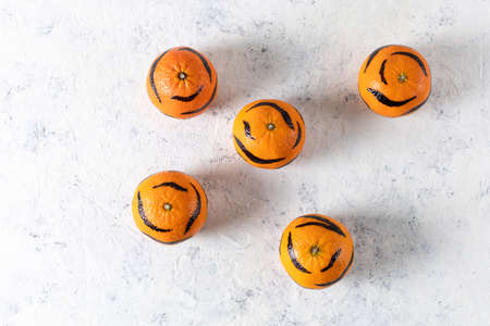 five tangerines with painted stripes on a white background. Concept for the new year of the tiger for children. Top view, flat layの写真素材