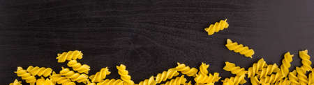 banner of Border of A pile of pasta spiral fusilli on dark black background with copyspaceの写真素材