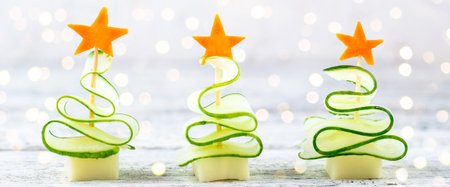 banner of Creative concept set christmas trees of cucumber, cheese and star of carrot. Funny kids food for new year party with copy spaceの写真素材