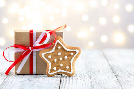 Gingerbread star and box of gift on bokeh lights background. Festive xmas background. Traditional Christmas atmosphere with bokeh. New year holiday concept with copy spaceの写真素材