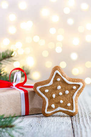Gingerbread star and box of gift on bokeh lights background. Festive xmas background. Traditional Christmas atmosphere with bokeh. New year holiday concept.の写真素材