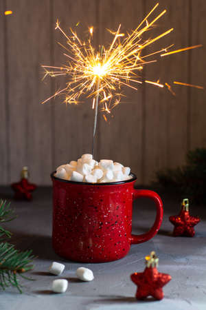 Red mug of christmas coffee or cocoa with marshmallows and sparklers on gray stone table. Xmas holiday conceptの写真素材