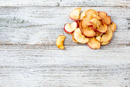 A pile of dried apples in slices on a white wooden background. Dried fruit chips. Healthy food. Top view with copyspaceの写真素材