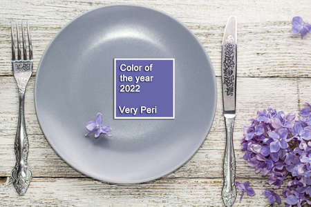 spring table setting with plate fork and knife decorated with lilac flowers on white wooden...