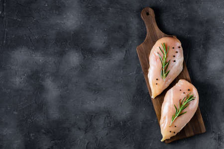 raw fresh chicken fillet with rosemary and spices on a dark background. Food background, cooking...