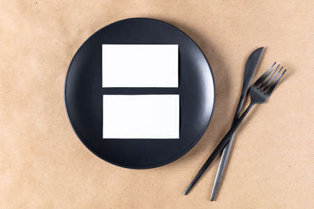 Blank white paper card on plate for mock up with dried spikelets decoration on craft beige...
