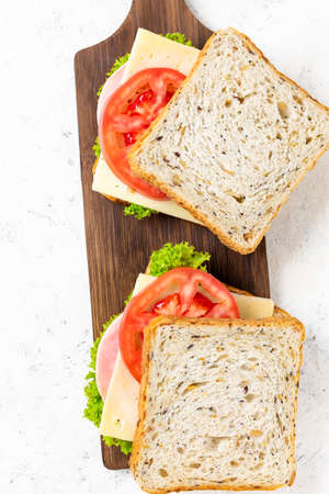 Two sandwiches with ham cheese tomatoes lettuce onions. Homemade sandwich with whole grain bread...