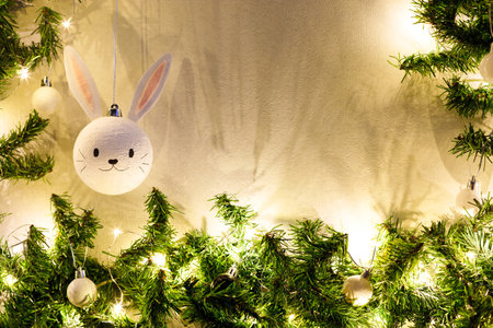 Handmade christmas ball with ears in the form of bunny hanging on the christmas tree. Happy Chinese new year of the rabbit zodiac sign. Symbol of the year 2023.の写真素材