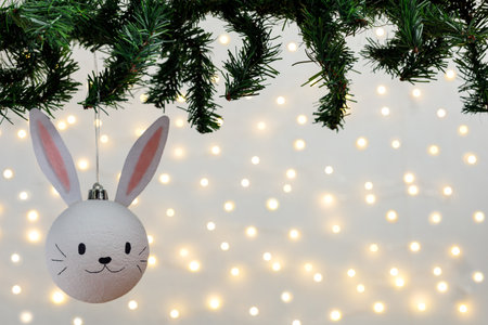 Handmade christmas ball with ears in the form of bunny hanging on the christmas tree. Happy Chinese...