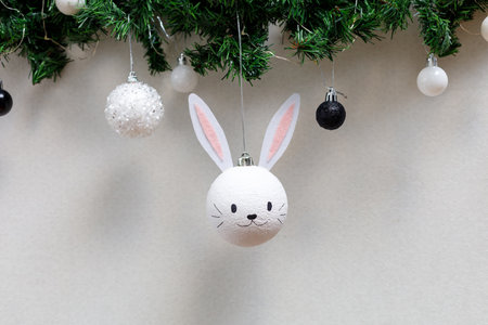 Handmade christmas ball with ears in the form of bunny hanging on the christmas tree. Happy Chinese...