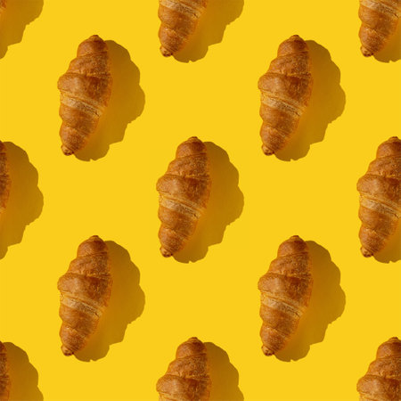 seamless pattern of tasty croissant on a yellow background with hard lightの写真素材