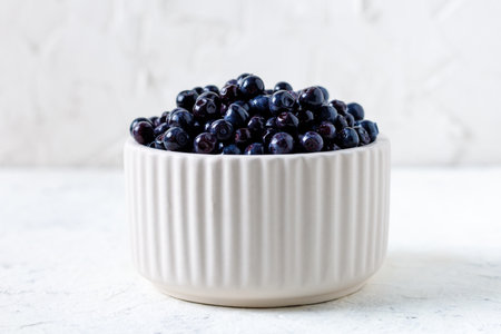 Fresh ripe blueberries in white ceramic bowl on tableの写真素材