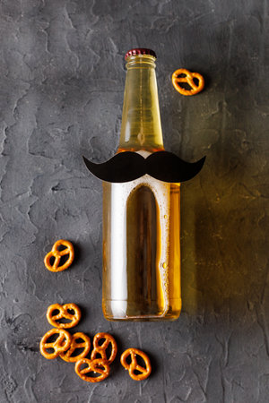 Bottle of beer with mustache with pretzels on gray background.  Concept of a party, father's day, bachelor party.の写真素材