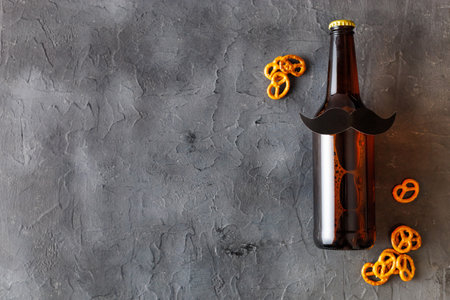 Bottle of beer with mustache with pretzels on gray background. movember. Concept of a party, father's day, bachelor party.の写真素材