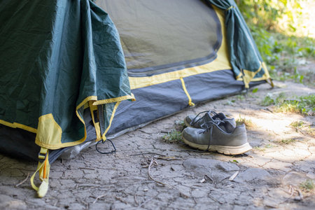 A pair of sport shoes near a tent in the camping forestの写真素材