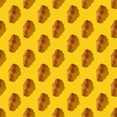 seamless pattern of tasty croissant on a yellow background with hard lightの写真素材